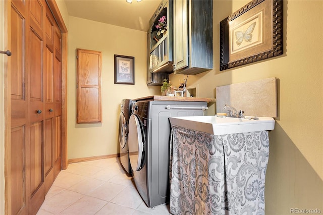 washroom with cabinet space, light tile patterned flooring, baseboards, and washer and clothes dryer