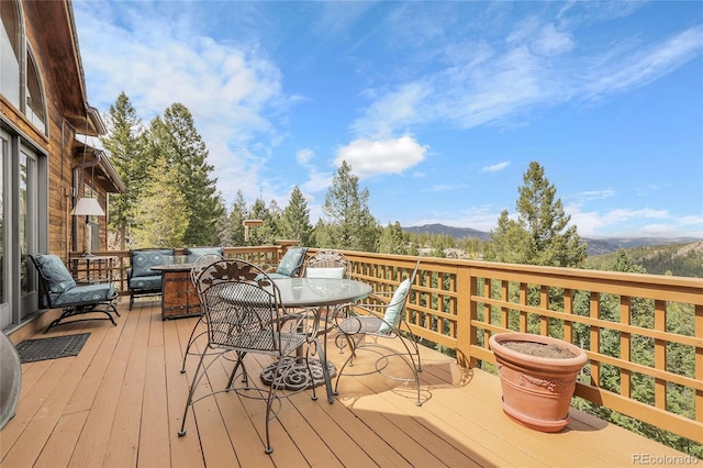 wooden deck featuring outdoor dining space and a mountain view