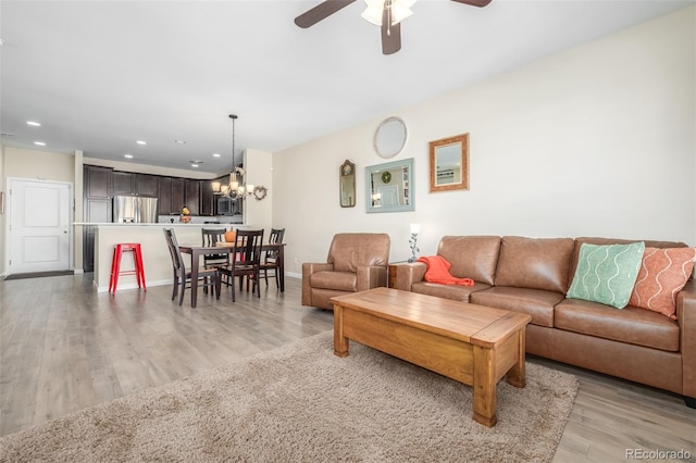 living room with light hardwood / wood-style flooring and ceiling fan with notable chandelier