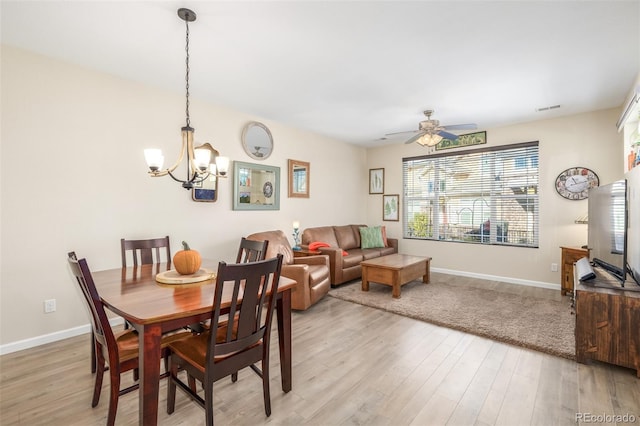 dining space featuring light hardwood / wood-style flooring and ceiling fan with notable chandelier