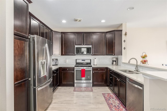 kitchen with sink, tasteful backsplash, light hardwood / wood-style floors, kitchen peninsula, and stainless steel appliances