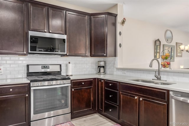 kitchen with dark brown cabinetry, sink, decorative backsplash, appliances with stainless steel finishes, and light wood-type flooring