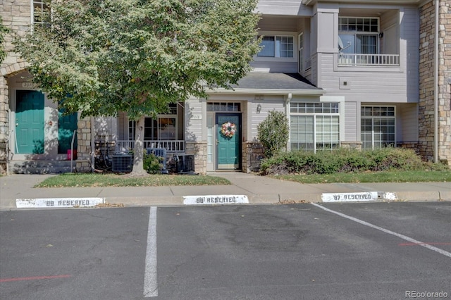9448 E Florida Ave Unit 1078, Denver, CO 80247 - view of front of property with uncovered parking, covered porch, stone siding, and cooling unit