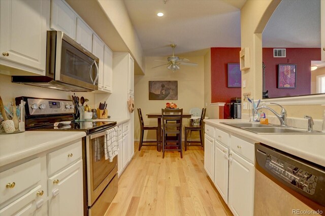 kitchen featuring sink, white cabinets, appliances with stainless steel finishes, light hardwood / wood-style floors, and ceiling fan