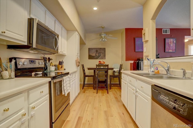 9448 E Florida Ave Unit 1078, Denver, CO 80247 - kitchen with appliances with stainless steel finishes, a sink, light wood finished floors, white cabinetry, and visible vents