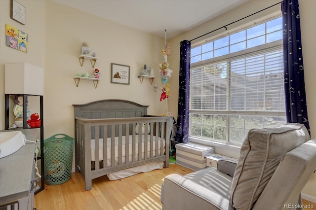 bedroom with a nursery area and hardwood / wood-style floors