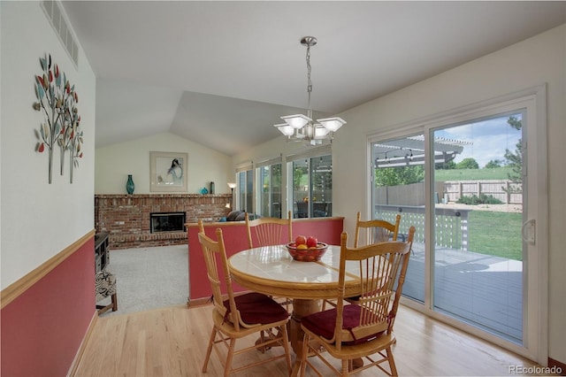 1825 Keota Ln, Superior, CO 80027 - dining room featuring light wood-style floors, a fireplace, a chandelier, and vaulted ceiling
