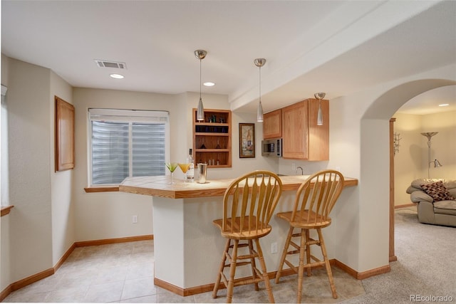 1825 Keota Ln, Superior, CO 80027 - kitchen with stainless steel microwave, a kitchen breakfast bar, arched walkways, a peninsula, and baseboards