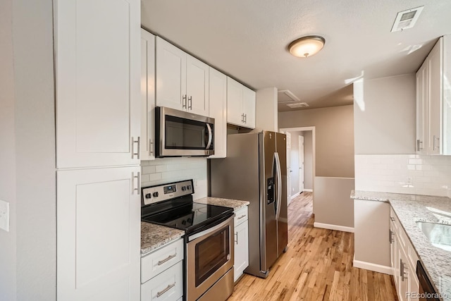 4804 N Raleigh St, Denver, CO 80212 - kitchen with stainless steel appliances, white cabinetry, light wood-style floors, decorative backsplash, and light stone countertops