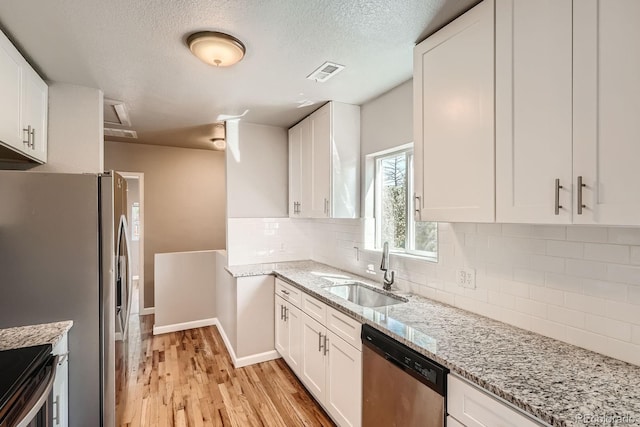 4804 N Raleigh St, Denver, CO 80212 - kitchen with stainless steel appliances, white cabinetry, light wood-style floors, tasteful backsplash, and light stone counters
