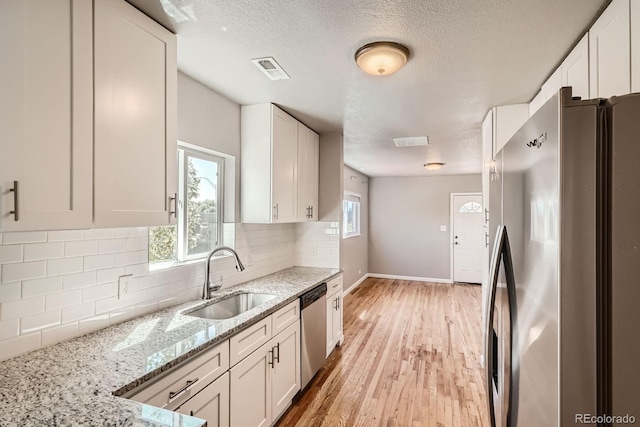 4804 N Raleigh St, Denver, CO 80212 - kitchen featuring stainless steel appliances, white cabinetry, backsplash, and a textured ceiling