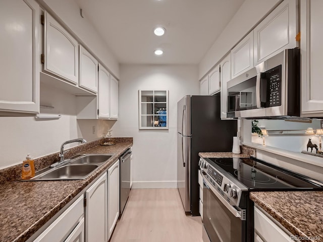 kitchen featuring a sink, dark countertops, appliances with stainless steel finishes, light wood finished floors, and baseboards