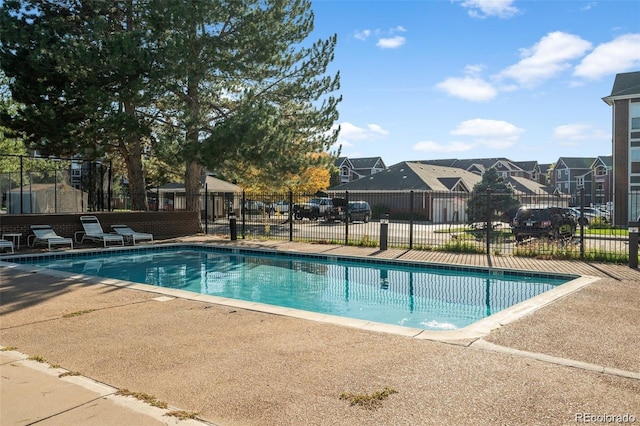 community pool with a residential view, a patio, and fence