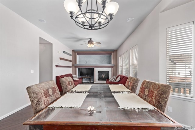 dining room featuring wood-type flooring, a tile fireplace, and ceiling fan with notable chandelier