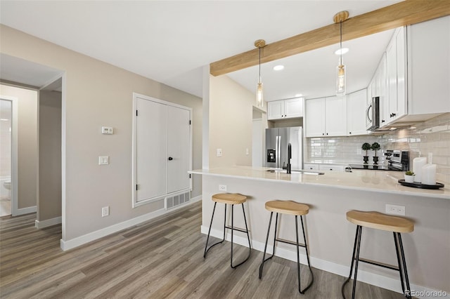 4274 S Salida Way Unit 3, Aurora, CO 80013 - kitchen with stainless steel appliances, a peninsula, decorative backsplash, light wood-type flooring, and baseboards