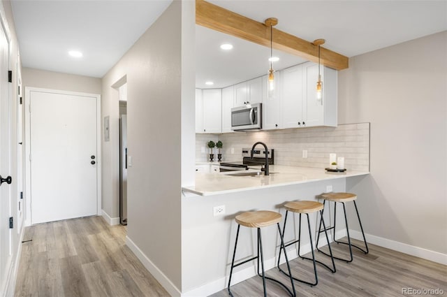 4274 S Salida Way Unit 3, Aurora, CO 80013 - kitchen featuring appliances with stainless steel finishes, a breakfast bar area, light wood-type flooring, backsplash, and recessed lighting