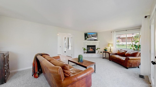 carpeted living area with a glass covered fireplace and baseboards