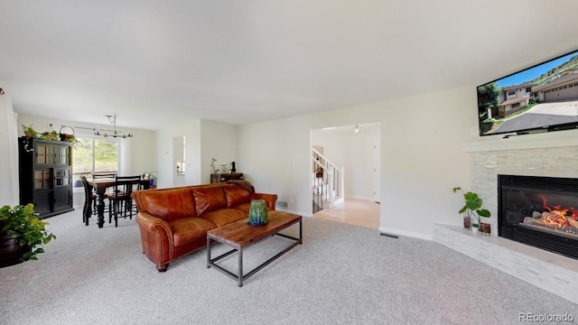 living area featuring carpet, stairs, and a glass covered fireplace
