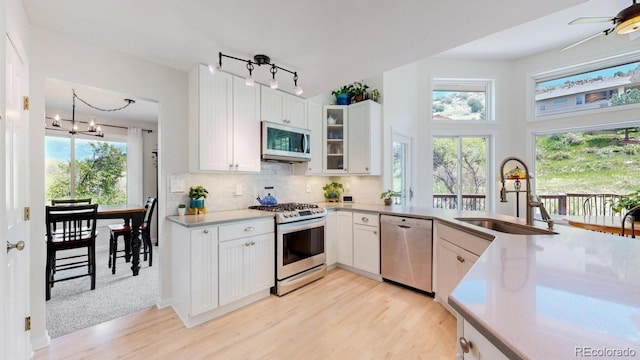 kitchen with appliances with stainless steel finishes, a sink, light wood-style floors, a chandelier, and light countertops