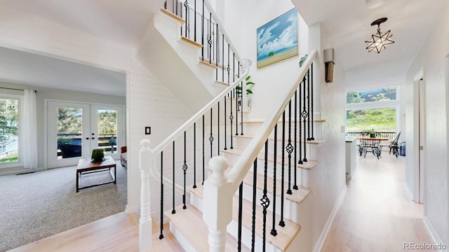 stairs featuring healthy amount of natural light, wood finished floors, french doors, and baseboards