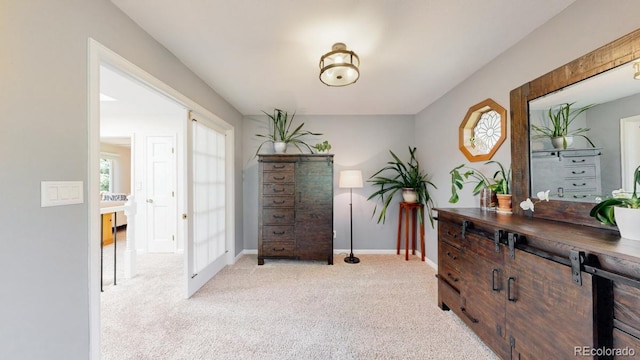 hall featuring light colored carpet and baseboards