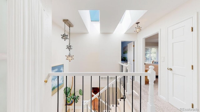 hallway featuring a skylight, an upstairs landing, and carpet flooring