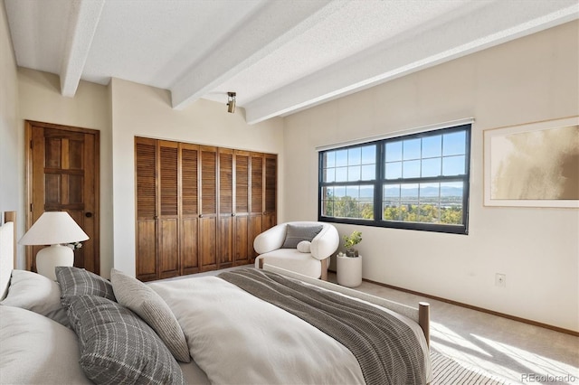 bedroom with beam ceiling, a closet, a textured ceiling, and carpet flooring