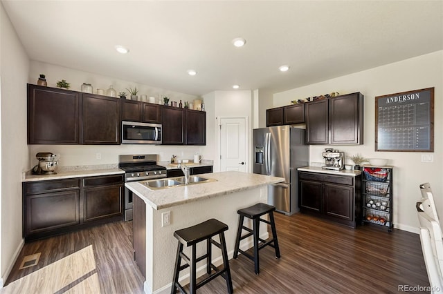 kitchen with sink, appliances with stainless steel finishes, dark hardwood / wood-style floors, and a kitchen island with sink