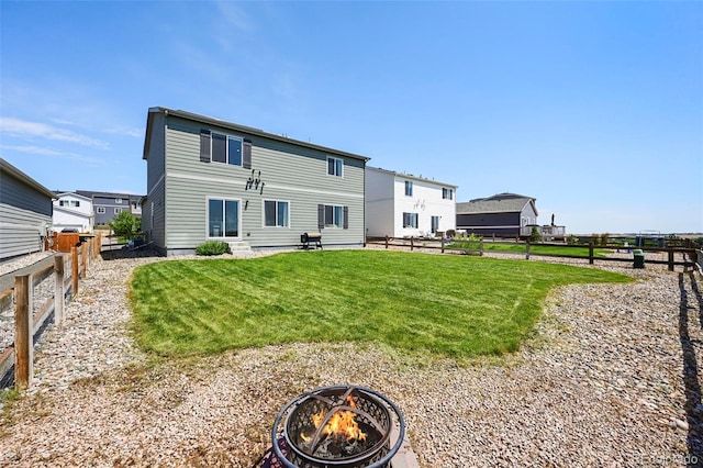 back of house with a yard and an outdoor fire pit