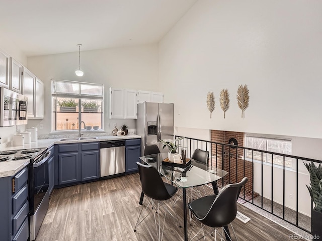 kitchen featuring stainless steel appliances, blue cabinets, sink, and hanging light fixtures