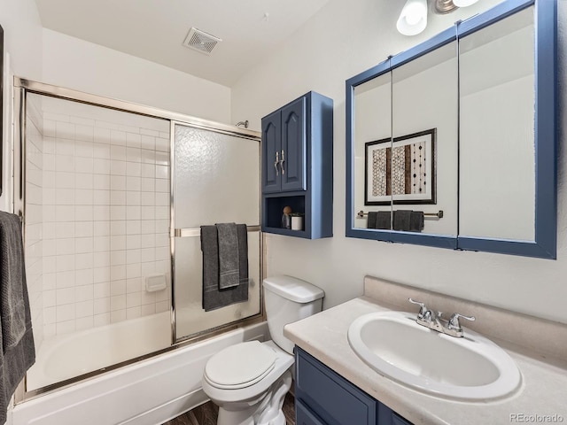 full bathroom featuring vanity, shower / bath combination with glass door, and toilet