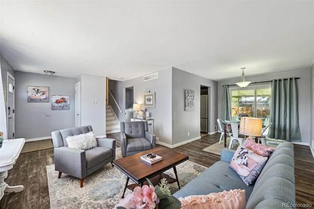 living area with stairs, baseboards, visible vents, and wood finished floors