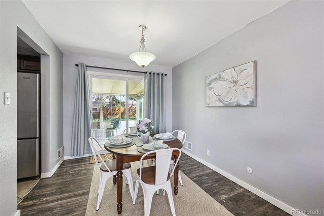 dining space with baseboards, dark wood finished floors, and visible vents