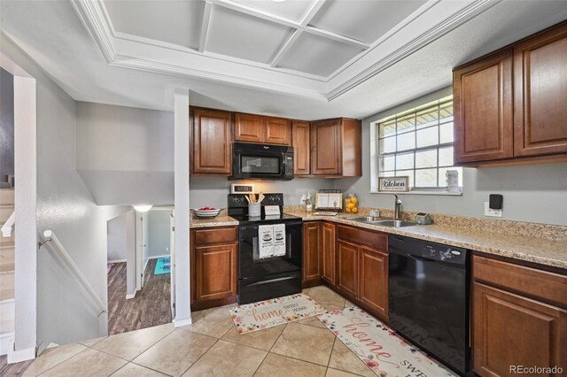 kitchen with light countertops, light tile patterned floors, a sink, and black appliances