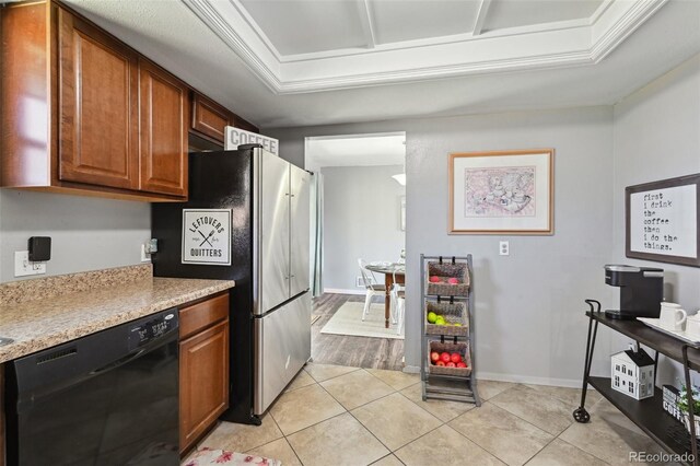 kitchen with freestanding refrigerator, dishwasher, light countertops, brown cabinets, and light tile patterned floors