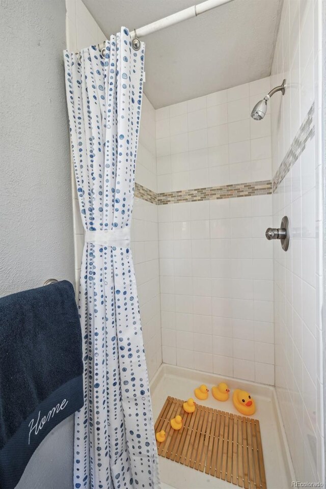 full bath featuring a textured wall and a tile shower