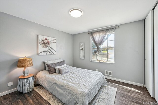 bedroom featuring baseboards, wood finished floors, and visible vents