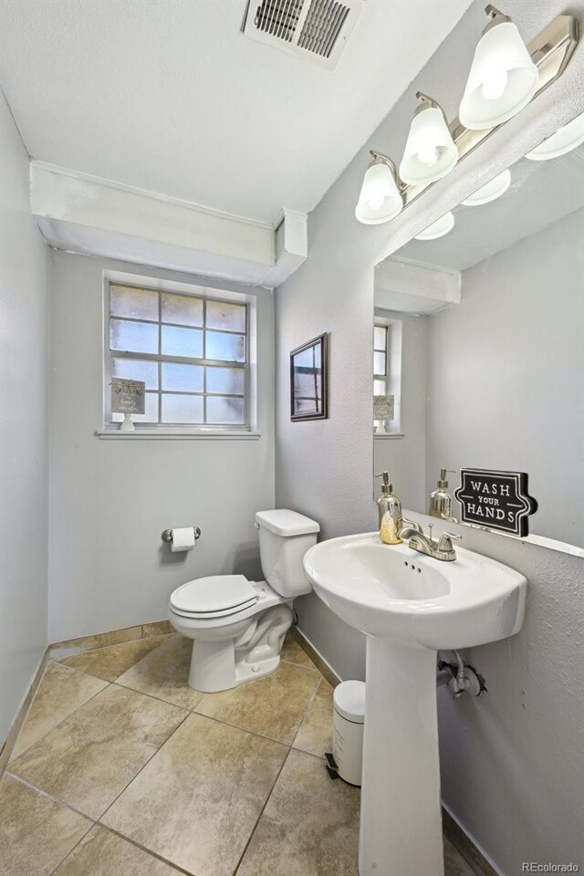 bathroom featuring baseboards, plenty of natural light, toilet, and visible vents