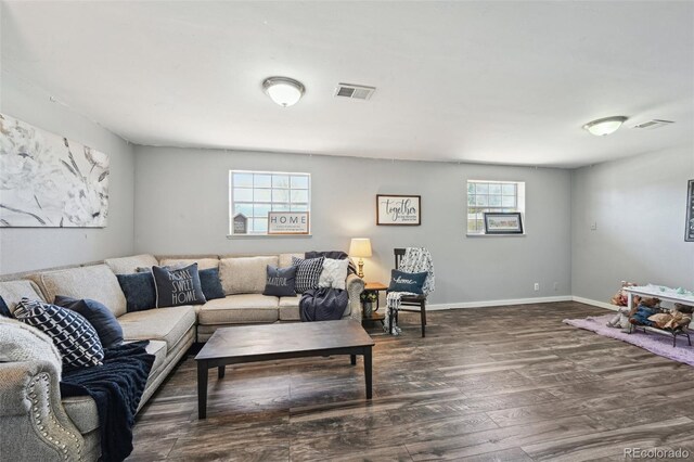 living area with baseboards, visible vents, and wood finished floors