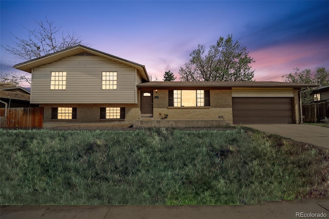 tri-level home featuring driveway, a garage, brick siding, fence, and a front lawn