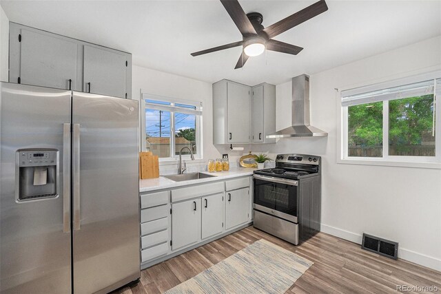 7625 Turner Dr, Denver, CO 80221 - kitchen featuring stainless steel appliances, wall chimney exhaust hood, a ceiling fan, and healthy amount of natural light
