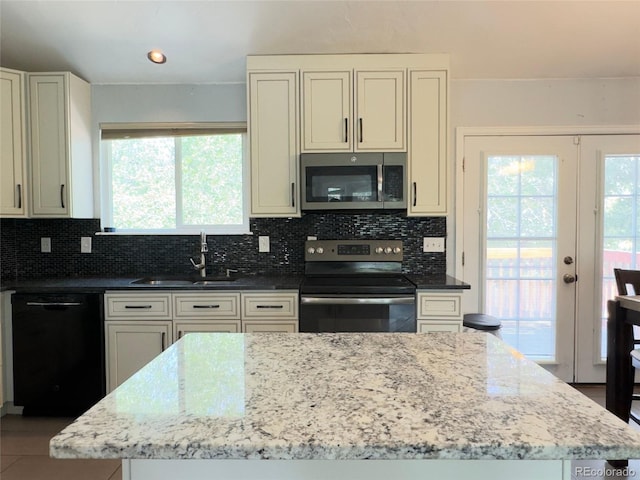 kitchen with light stone counters, stainless steel appliances, sink, and plenty of natural light