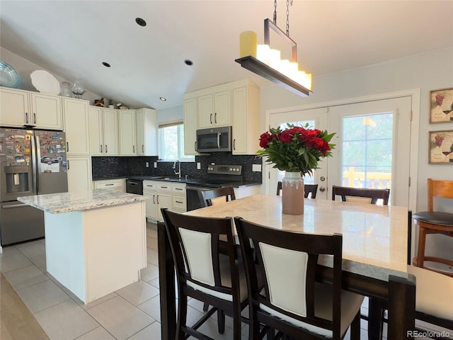 kitchen with light tile patterned flooring, decorative light fixtures, decorative backsplash, a center island, and stainless steel appliances