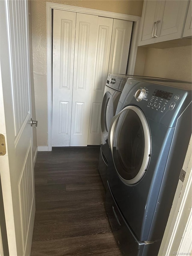 washroom featuring separate washer and dryer, dark hardwood / wood-style flooring, and cabinets