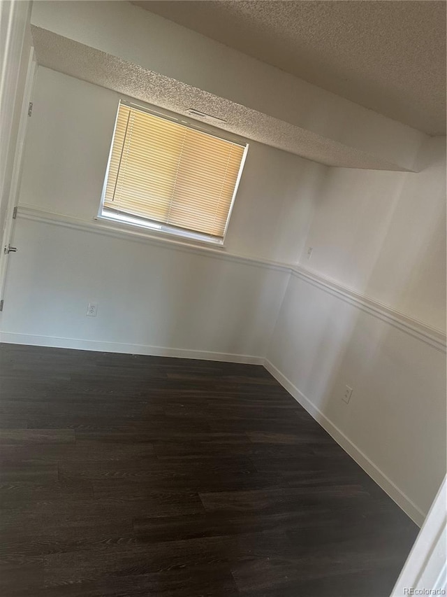 unfurnished room featuring dark hardwood / wood-style floors and a textured ceiling