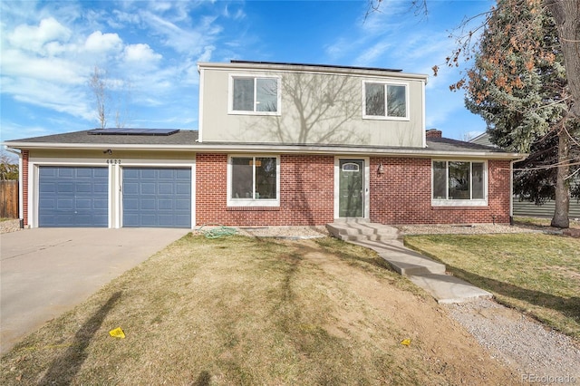 view of front of house with roof mounted solar panels, concrete driveway, a front yard, a garage, and brick siding