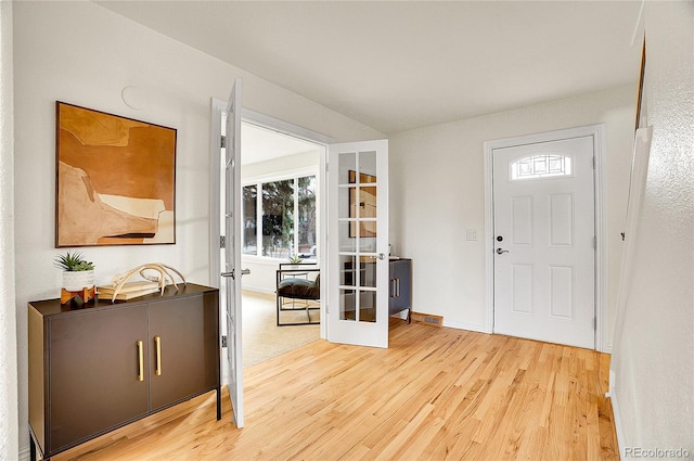 foyer entrance with french doors, baseboards, and light wood-style floors