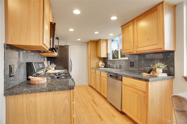 kitchen with tasteful backsplash, light brown cabinetry, light wood-type flooring, appliances with stainless steel finishes, and a sink