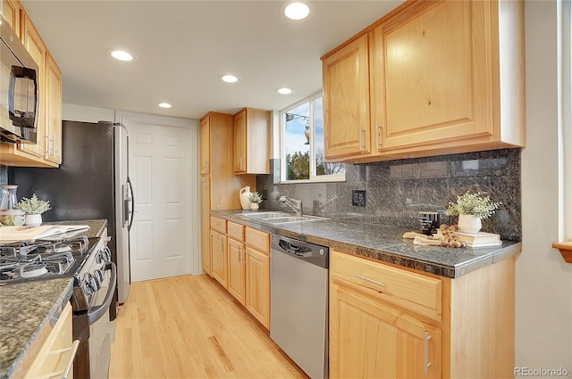 kitchen with light wood finished floors, light brown cabinets, stainless steel appliances, and a sink