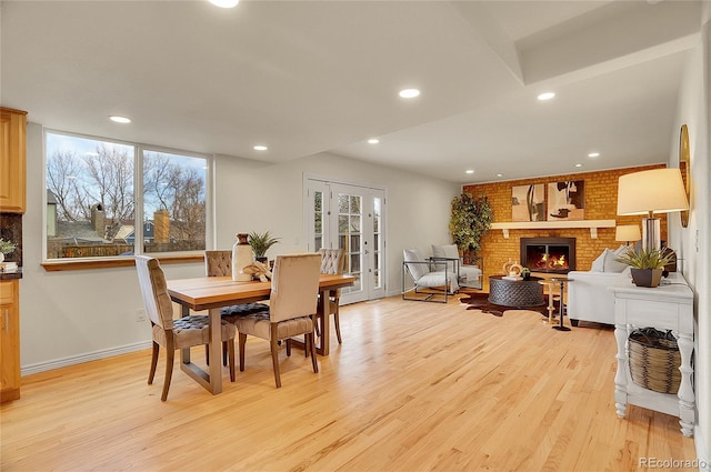 dining room with recessed lighting, a wealth of natural light, a brick fireplace, and light wood-style flooring